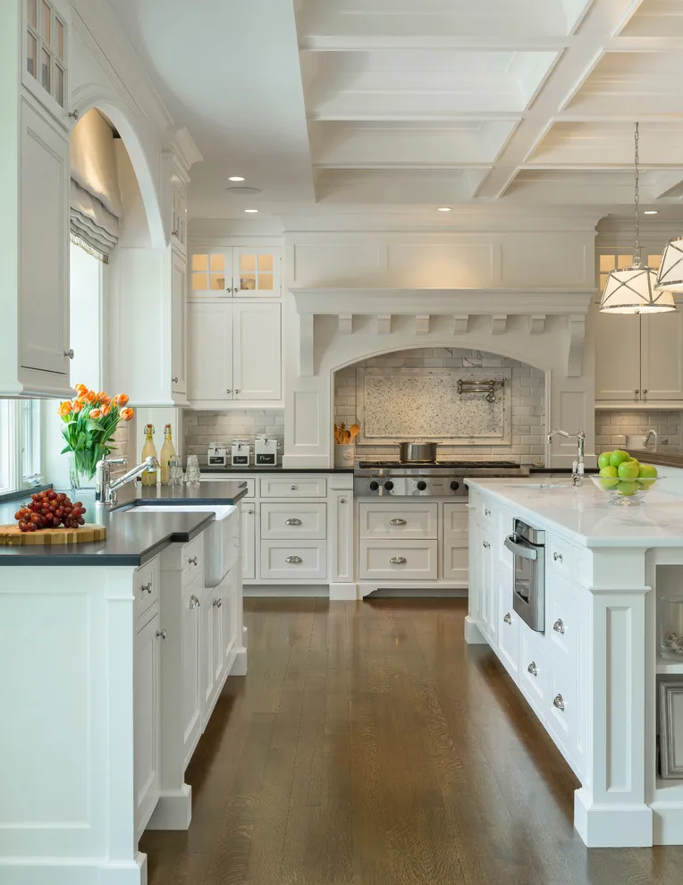 White paneled cabinets flank a broad pale range surround in a bright kitchen