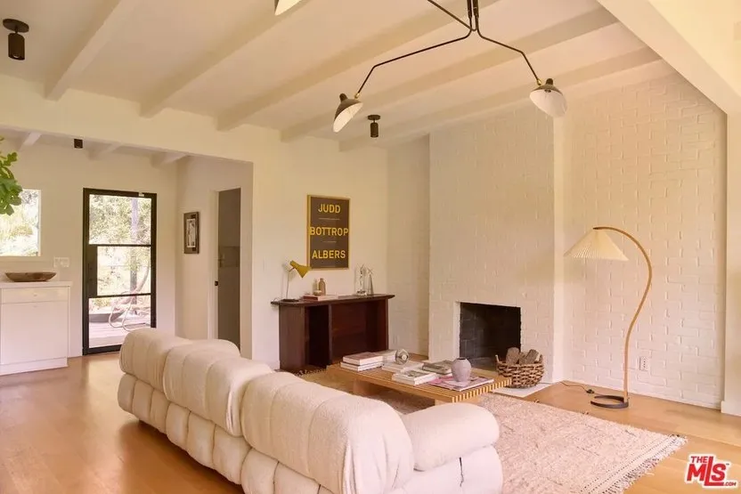 A low pale sofa sits below light walls and exposed ceiling details.