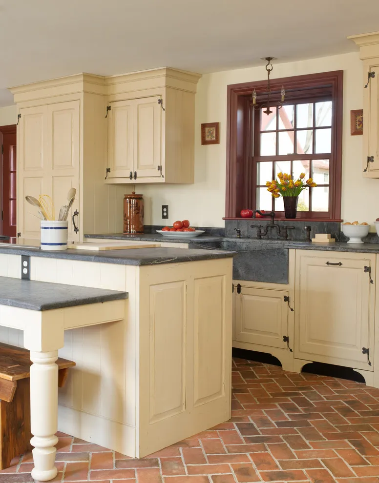 Cream cabinet fronts meet a brick-patterned floor beside a timber-framed window