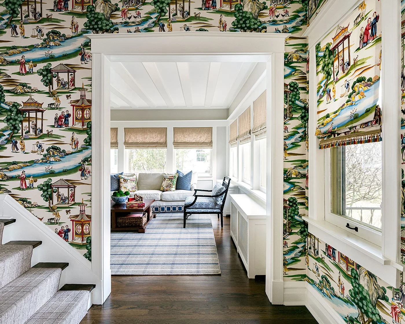 Colorful scenic wallpaper and a matching window blind surround a stair landing beside a pale reading room