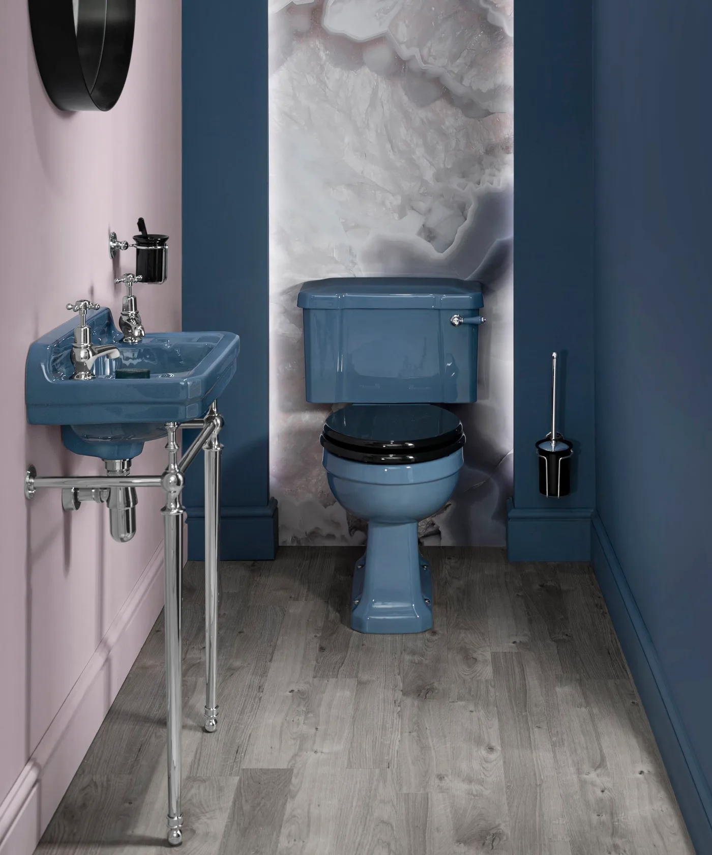 Blue walls surround a matching blue toilet and wall-mounted basin beside pale pink and veined white panels