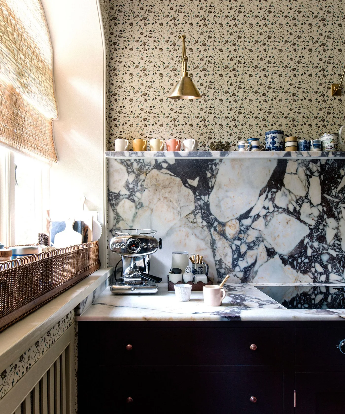 Country coffee corner with fine floral wallpaper above strongly veined backsplash and pale counter