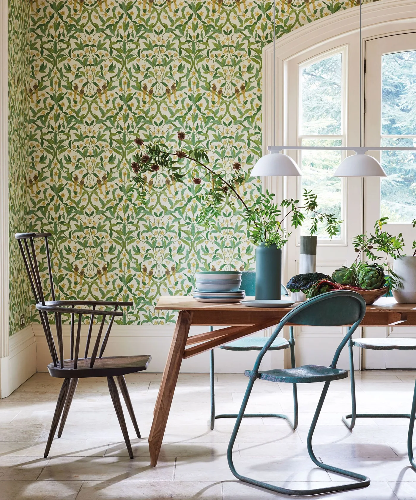 Country dining corner with green leafy wallpaper, wood table, spindle chair and pale window trim