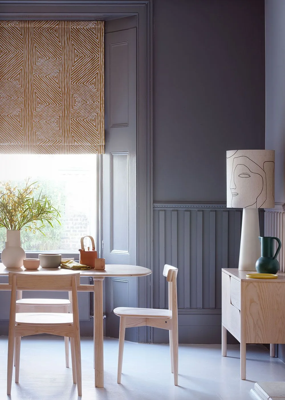 Gray dining corner with narrow lower-wall paneling, framed upper panels and a small pale table