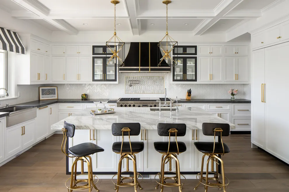 White cabinetry frames a dark hood above a pale island and black stools