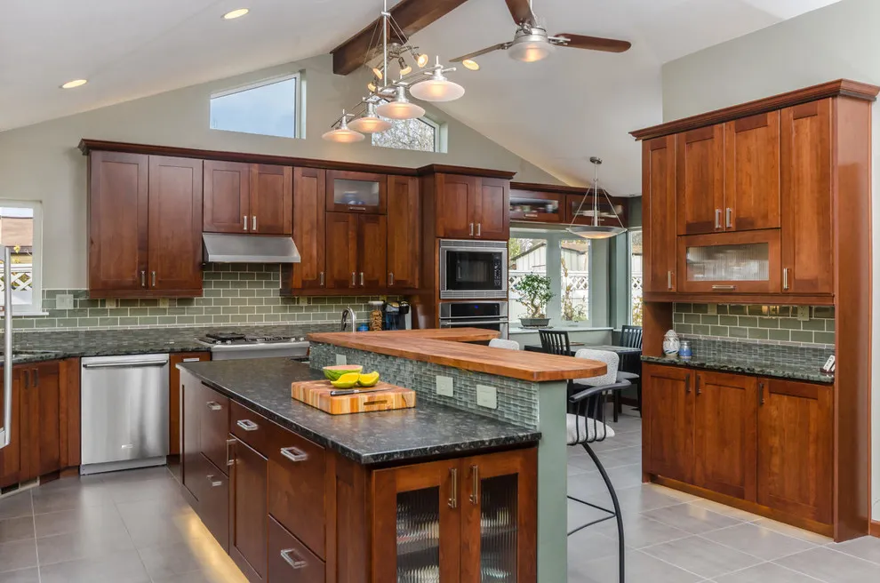 Warm wood cabinetry includes glass-front doors above a small island with a dark worktop