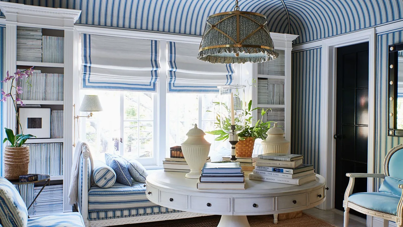 Country sitting room with blue striped wallpaper on walls and curved ceiling, pale built-ins and woven pendant