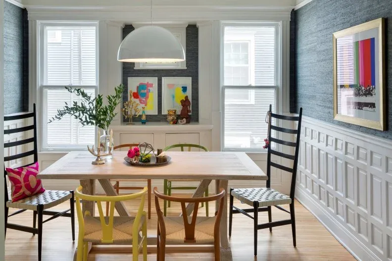 Dining room with tall black end chairs, smaller wood chairs, a pale table, blue-gray textured walls and a white dome pendant
