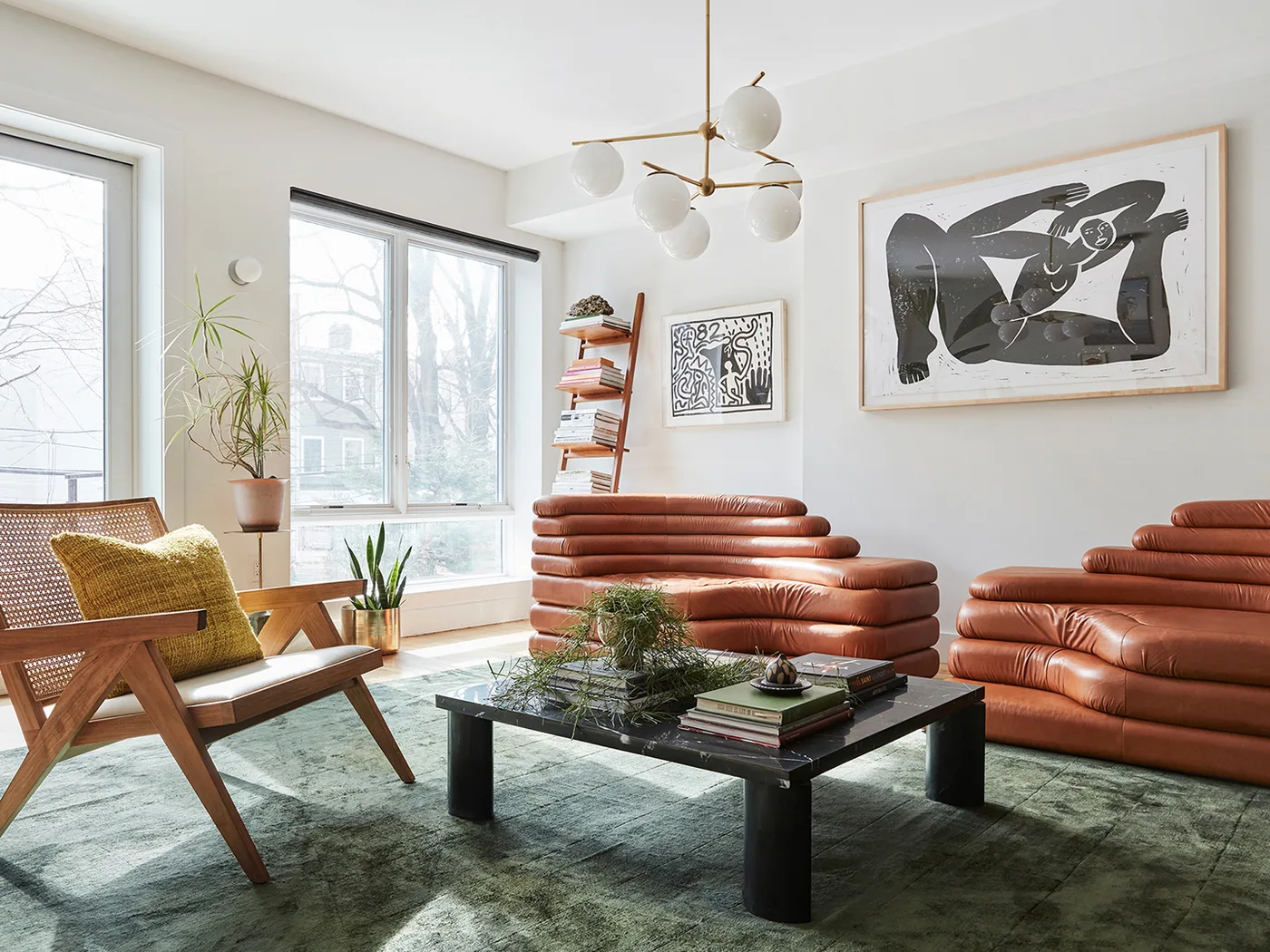Two brown leather sofas with tiered backs face a dark square table on a green rug in a pale room