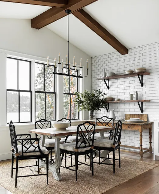 Dark open-backed chairs sit around a timber table below a bright pitched ceiling.
