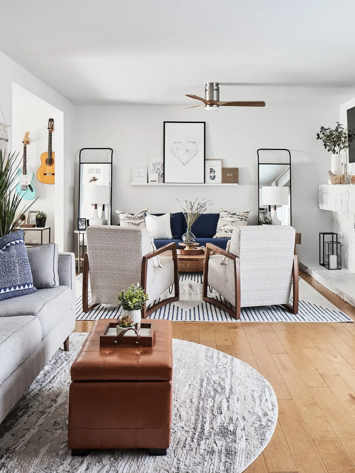 Pale lounge seating in front of two timber-framed armchairs and a blue sofa on a separate striped rug