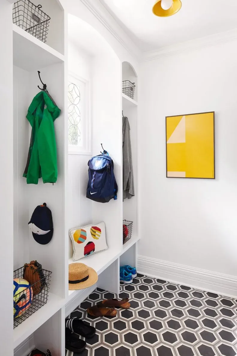 White narrow entry storage with slim bench, coat hooks, arched upper recesses, wire baskets and dark geometric floor