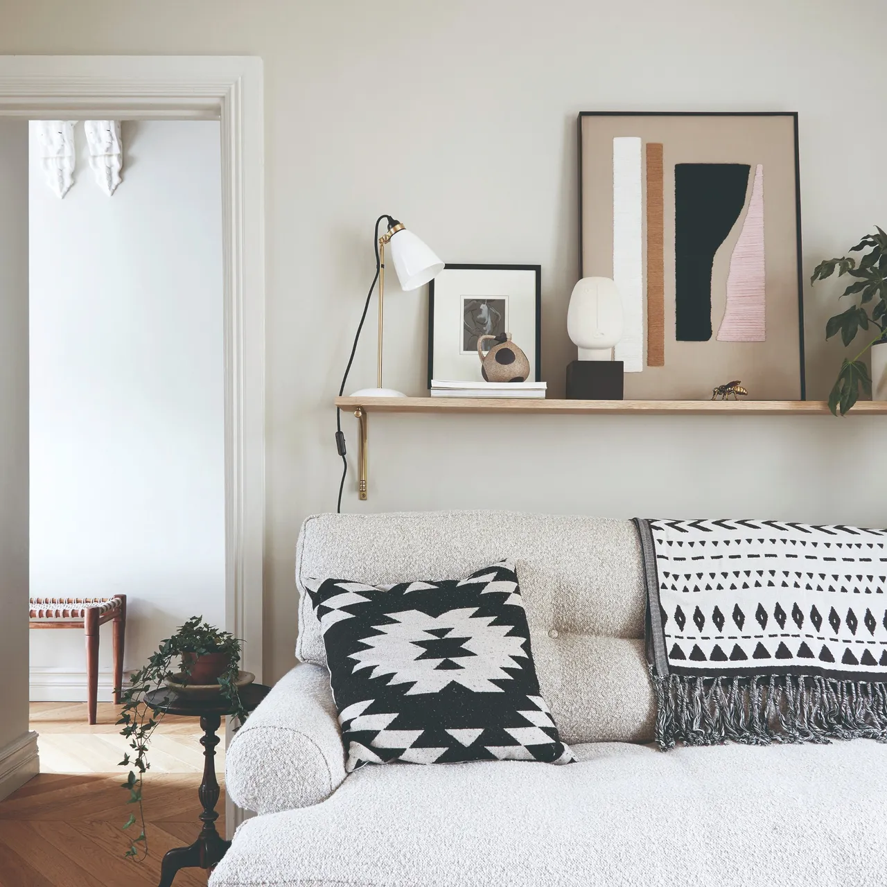 A pale sofa with patterned cushions sits beneath a narrow display shelf